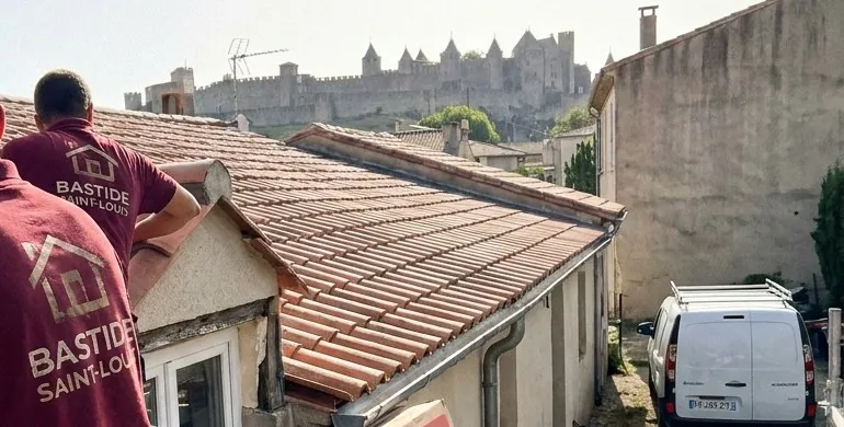Toits en tuile canal à Carcassonne avec les tours de la Cité médiévale à l’horizon